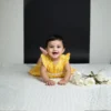 Yellow cotton infant frock playful pose, cozy and flexible baby clothing