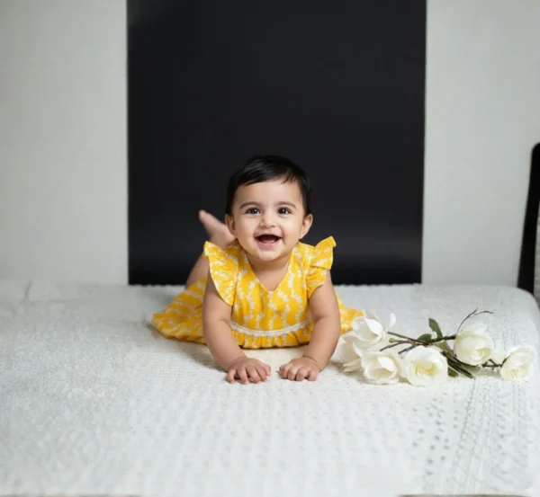 Yellow cotton infant frock playful pose, cozy and flexible baby clothing