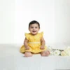 Yellow cotton infant frock front view, lightweight and stylish baby wear