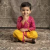 Fuchsia Bandhej Angrakha with Dhoti for boys sitting pose, yellow Dhoti and patterned top